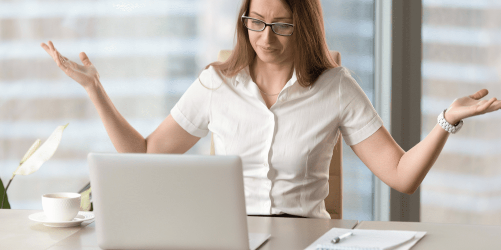 Woman with hands up at desk in front of laptop showing frustration with slow loading website