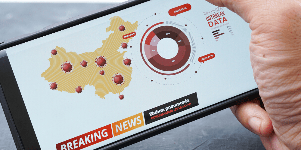 Hand holding smartphone showing national coronavirus outbreak map and virus statistics