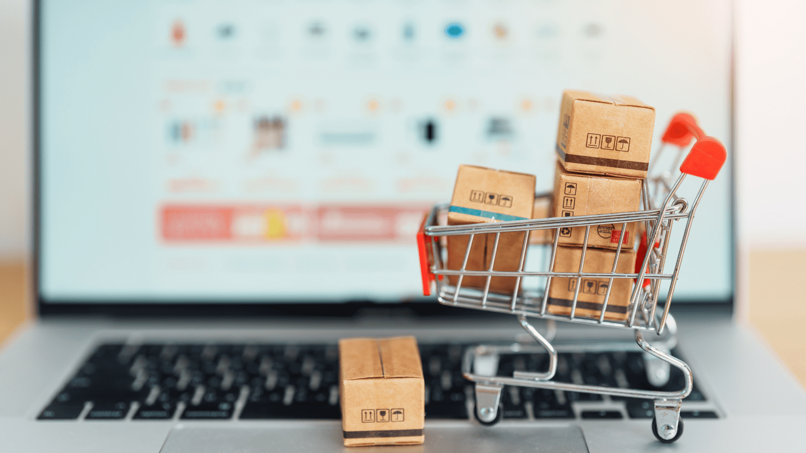 Why Consumers Prefer Marketplaces Over Brand Websites, mini shopping cart with boxes in front of laptop displaying amazon marketplace website