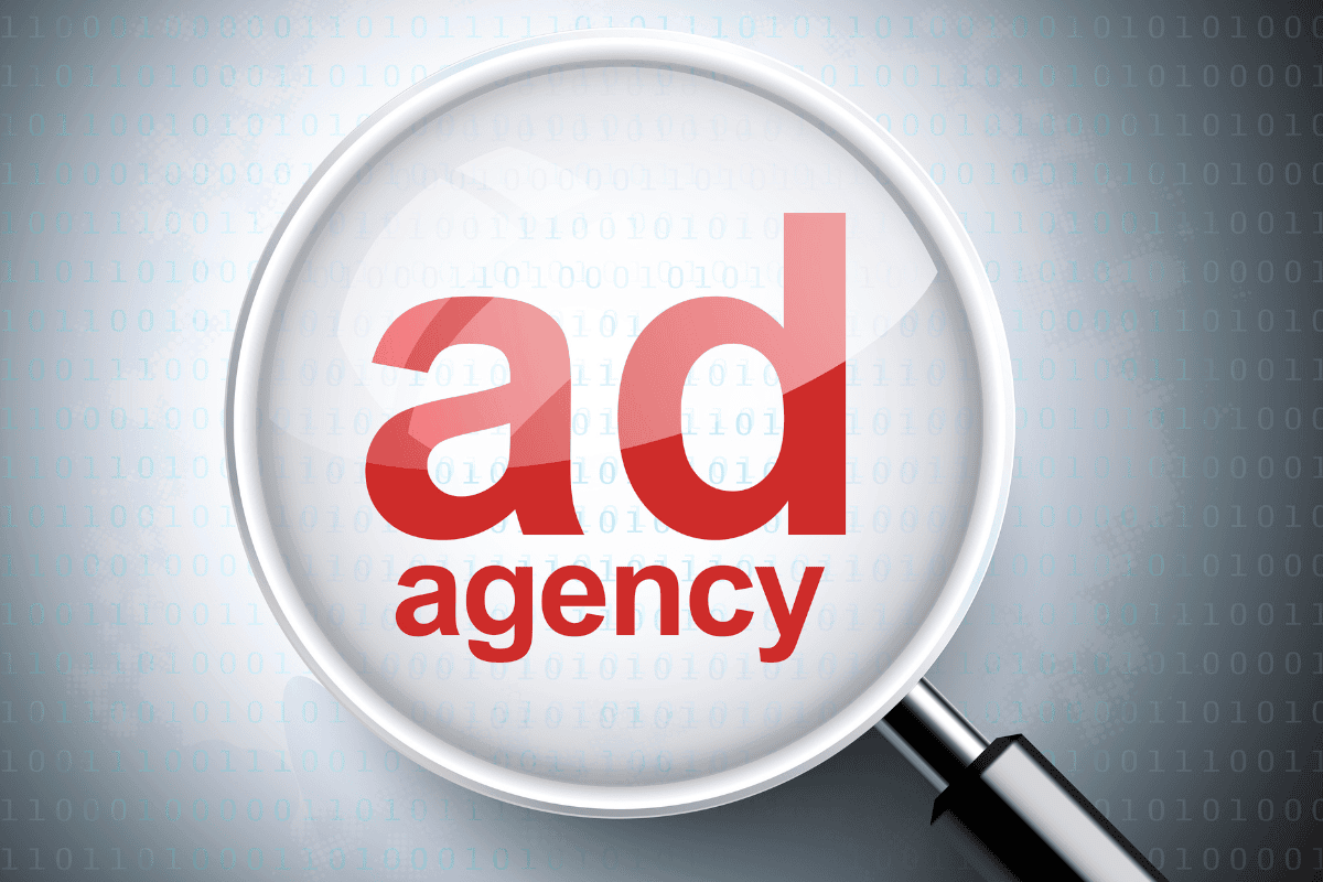 Magnifying glass highlighting an advertising agency, representing how businesses evaluate and compare full-service media agencies for planning, integration, accountability, and performance.